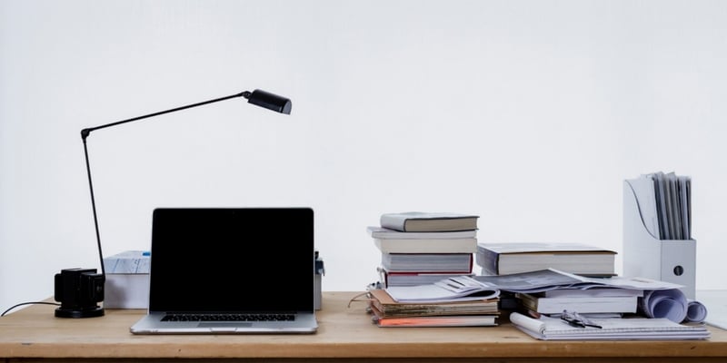 Desk filled books and a laptop.